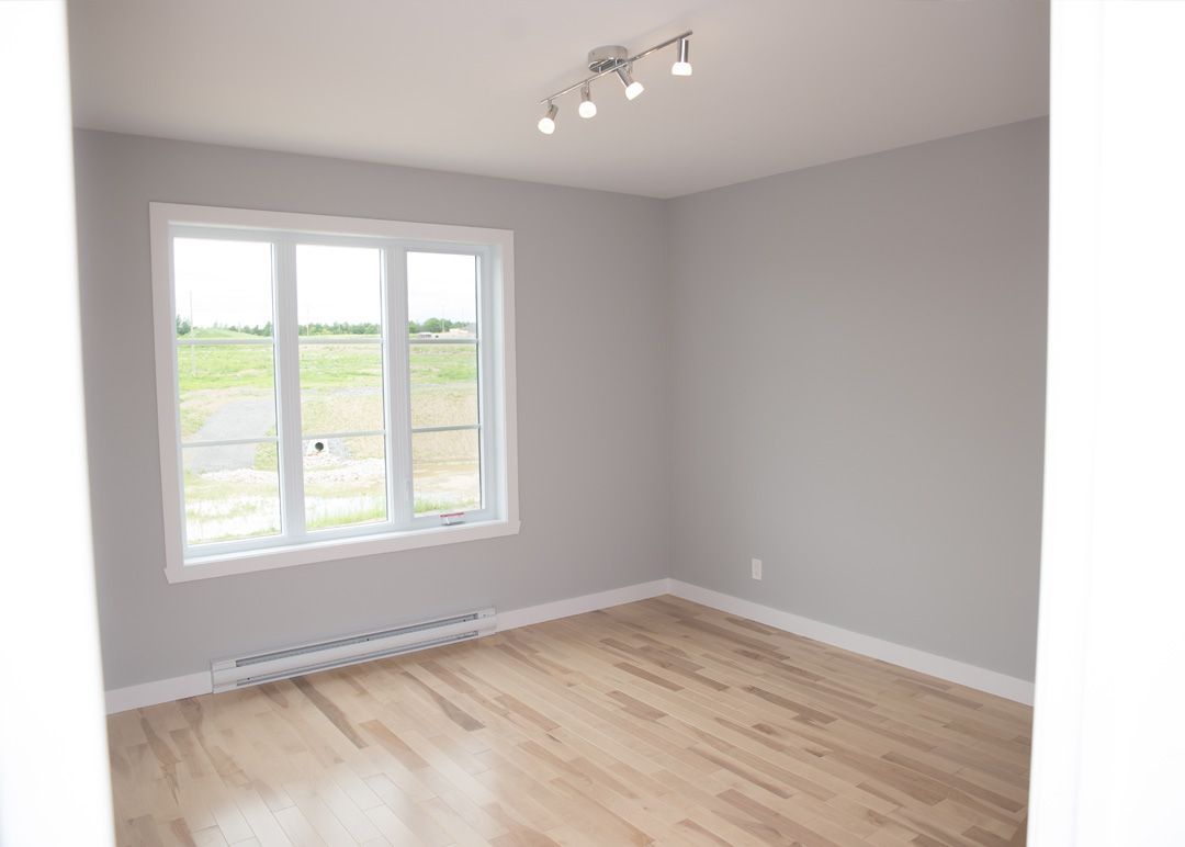 Une pièce vide avec du parquet et une grande fenêtre.