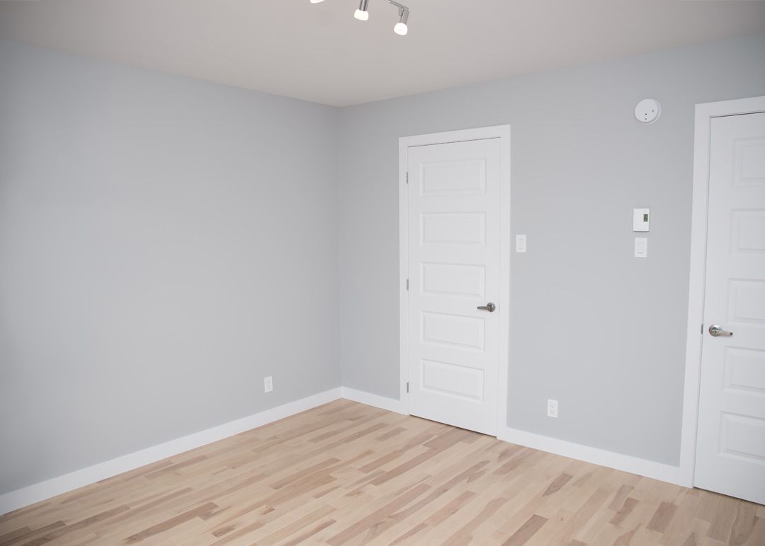 Une pièce vide avec du parquet et des murs gris