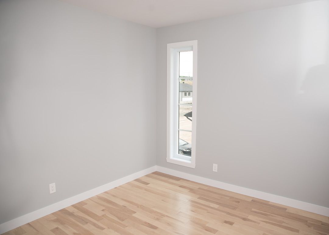 Une pièce vide avec du parquet et une grande fenêtre.