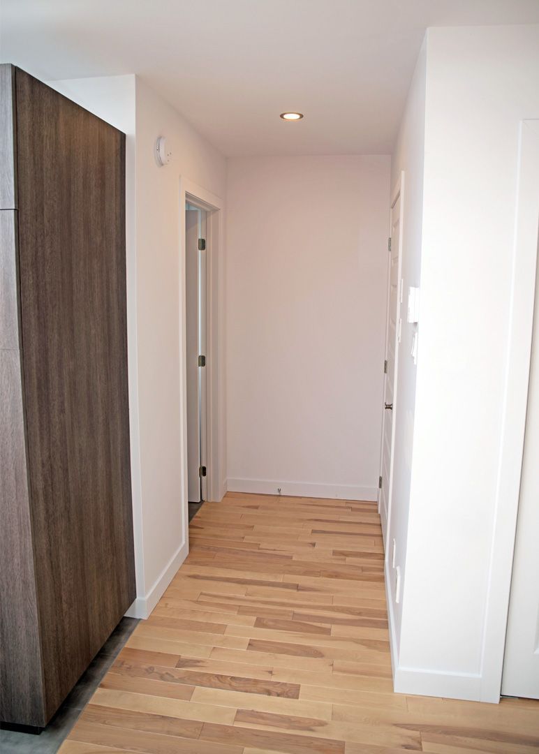 Un couloir avec parquet et murs blancs
