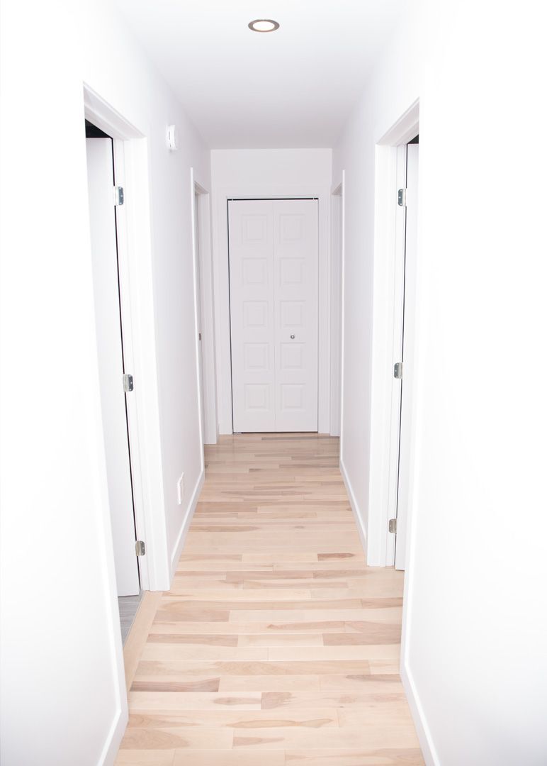 Un long couloir avec du parquet et des murs blancs