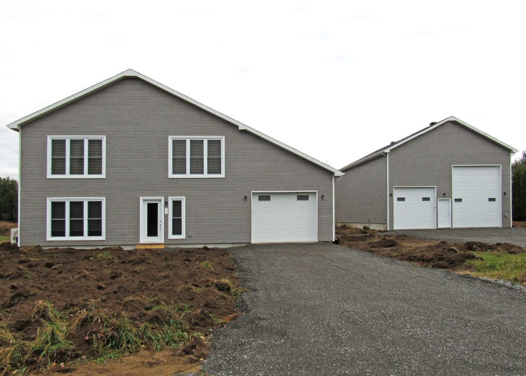 Une grande maison avec deux garages et une allée en gravier