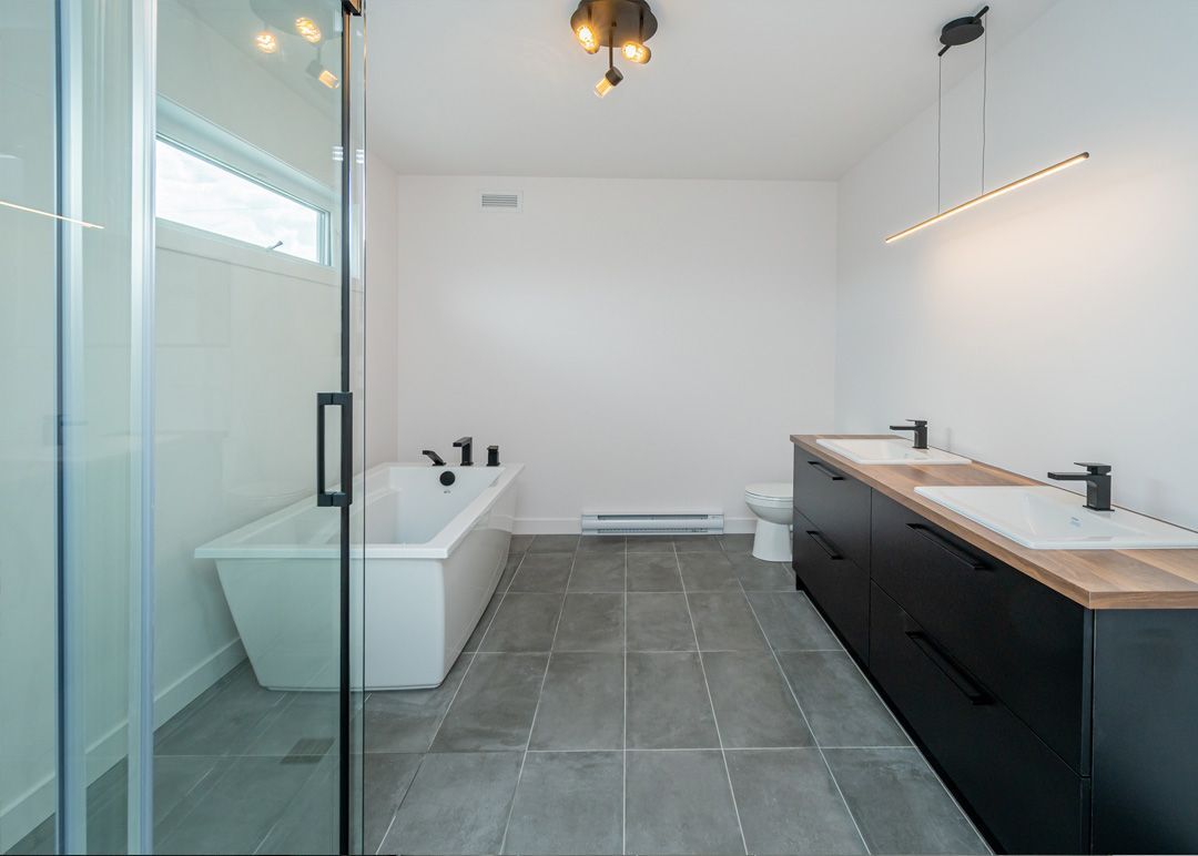 Une salle de bain avec baignoire, lavabos, WC et douche.