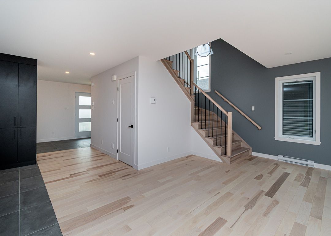Un salon avec parquet et escaliers dans une maison.