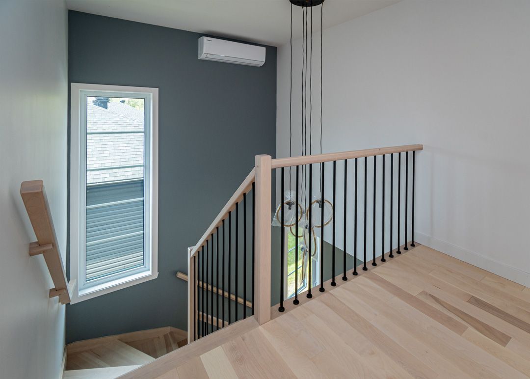 Un escalier avec une rampe en bois et une fenêtre dans une maison.