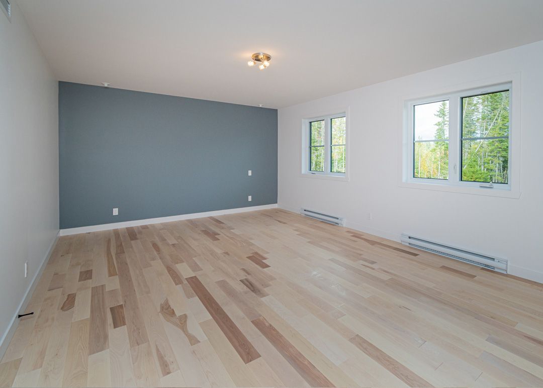 Une pièce vide avec du parquet et un mur bleu