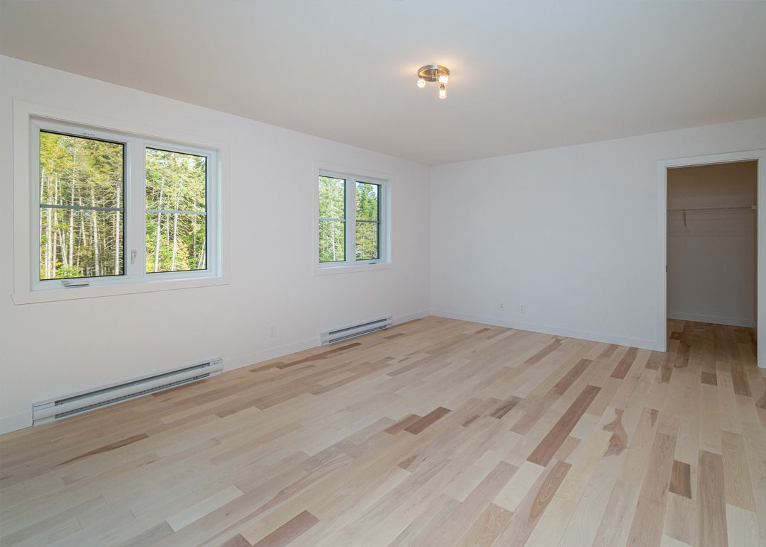 Une pièce vide avec du parquet et des murs blancs
