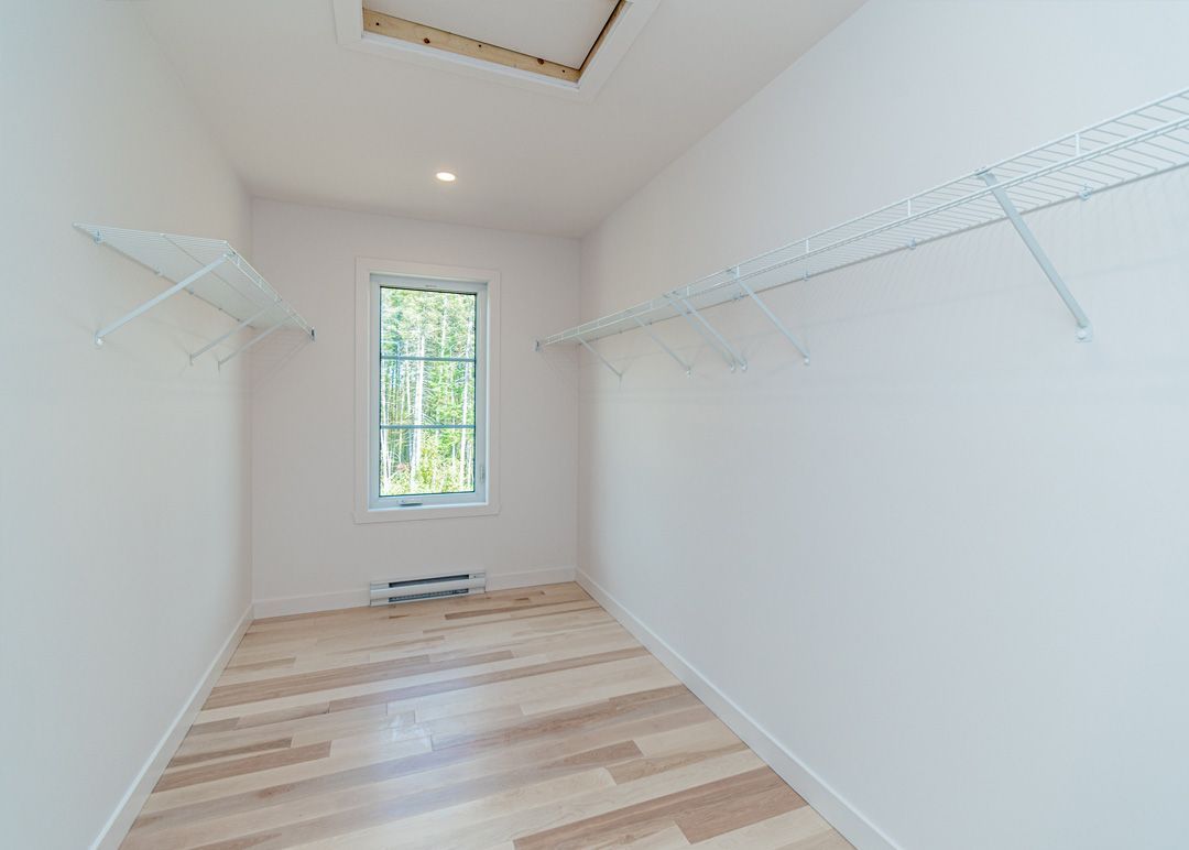 Un dressing vide avec du parquet et une fenêtre.