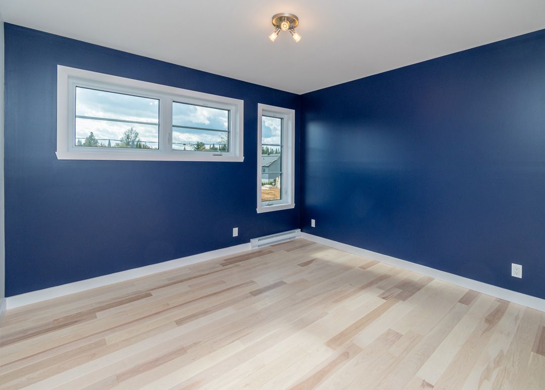 Une pièce vide avec des murs bleus et du parquet.