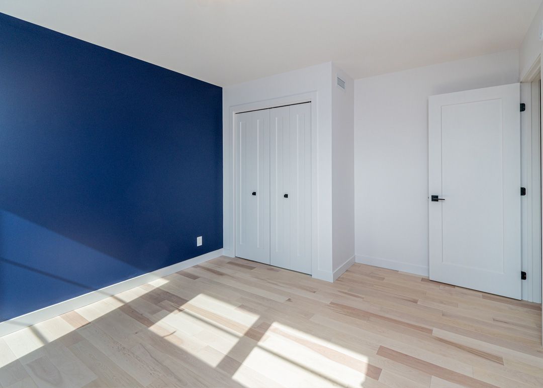 Une pièce vide avec un mur bleu et des portes blanches