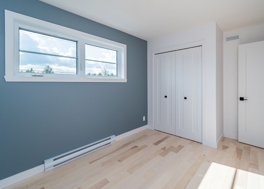 Une pièce vide avec un mur bleu et une fenêtre.