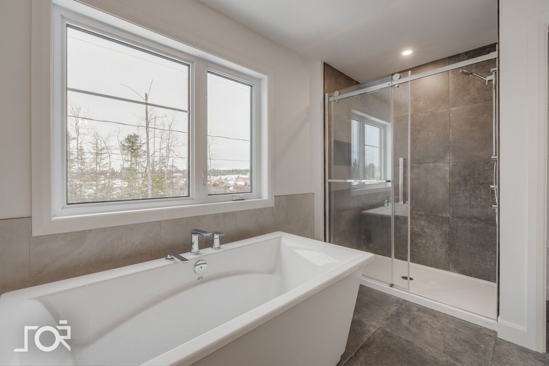 Une salle de bain avec baignoire, douche et fenêtre.