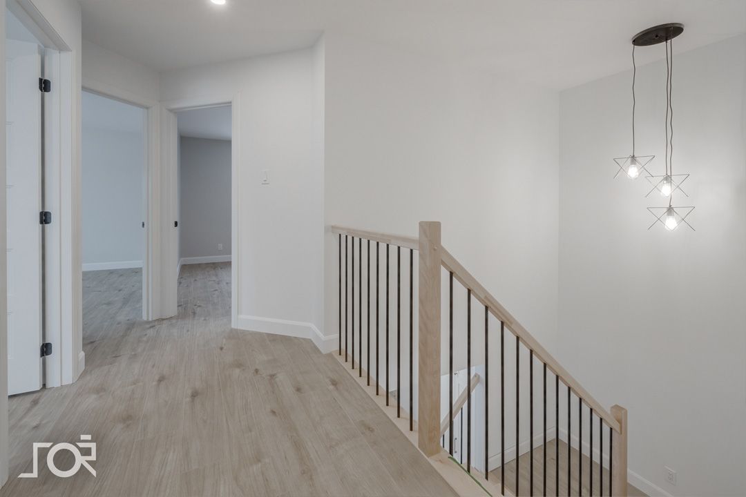 Un couloir vide avec une balustrade en bois et des escaliers menant au deuxième étage.