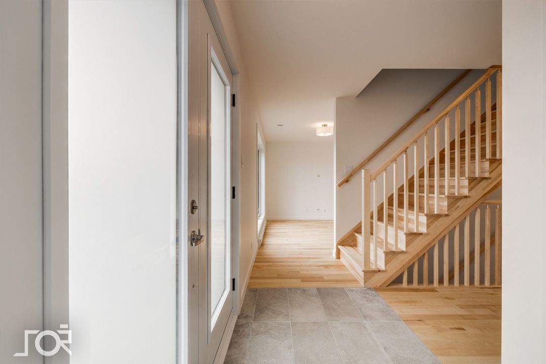 Un couloir avec un escalier en bois menant au deuxième étage