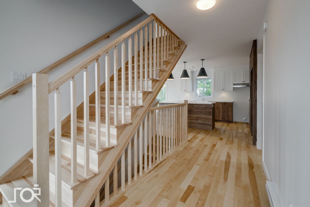 Un escalier en bois avec une rampe blanche dans un couloir