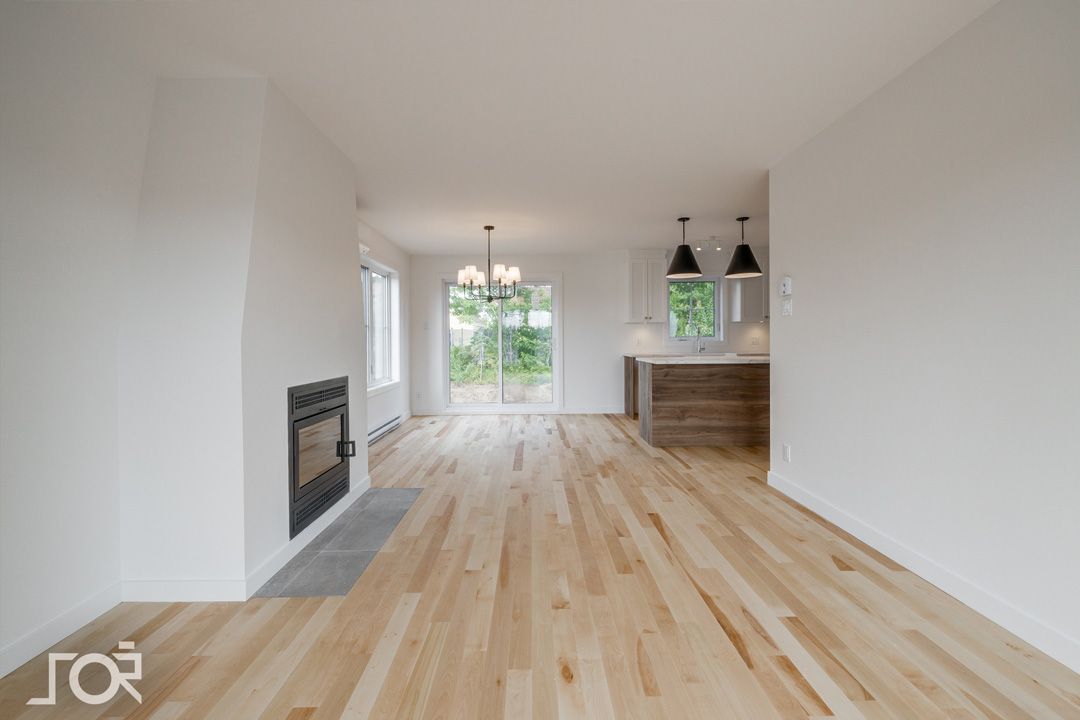 Un salon vide avec du parquet et des murs blancs