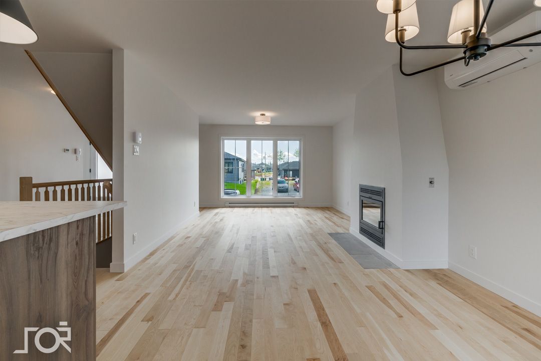 Un salon vide avec du parquet et une cheminée