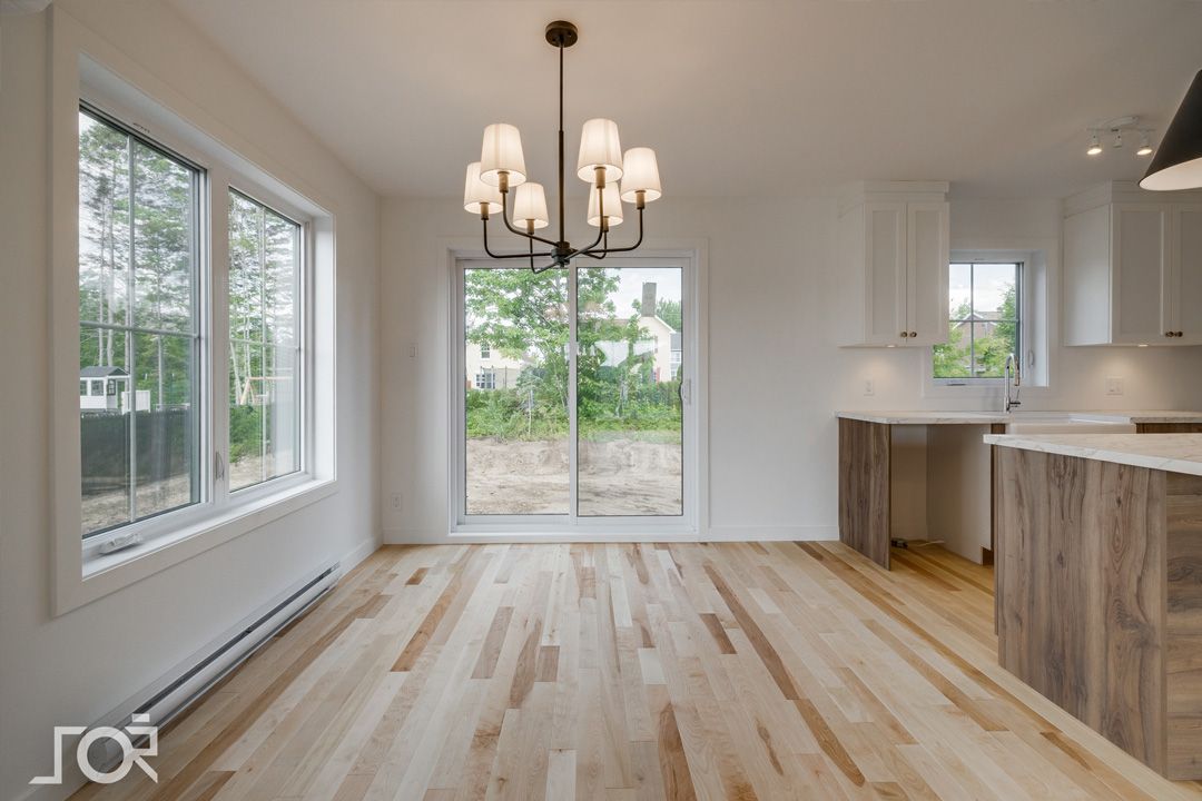 Une pièce vide avec du parquet et un lustre