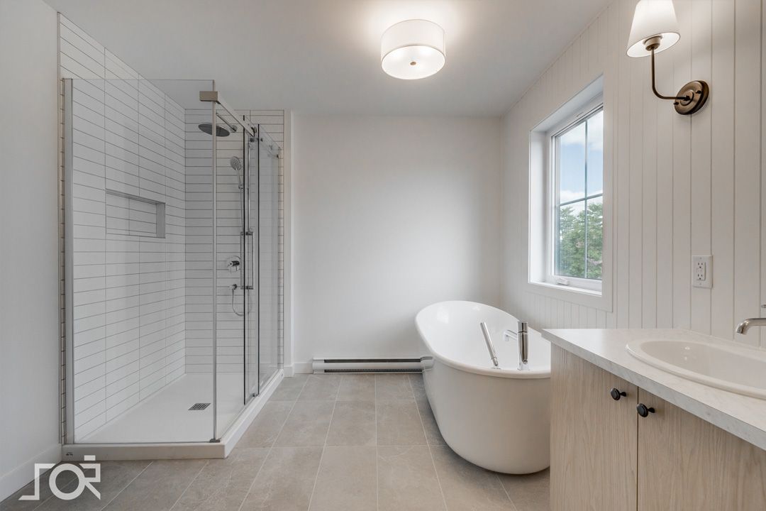 Une salle de bain avec baignoire, lavabo, douche et fenêtre.