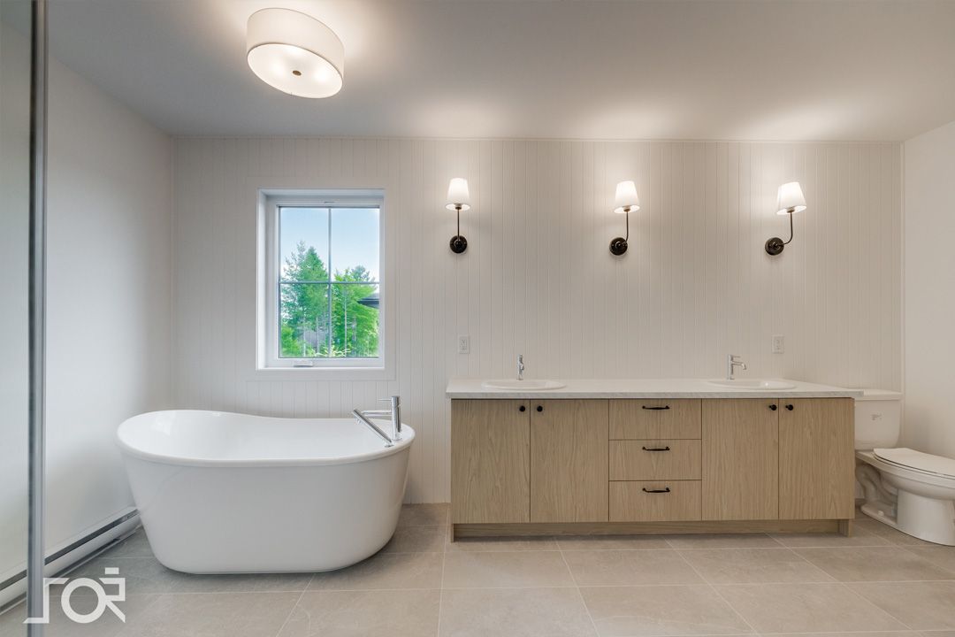 Une salle de bain avec baignoire, lavabo et fenêtre.