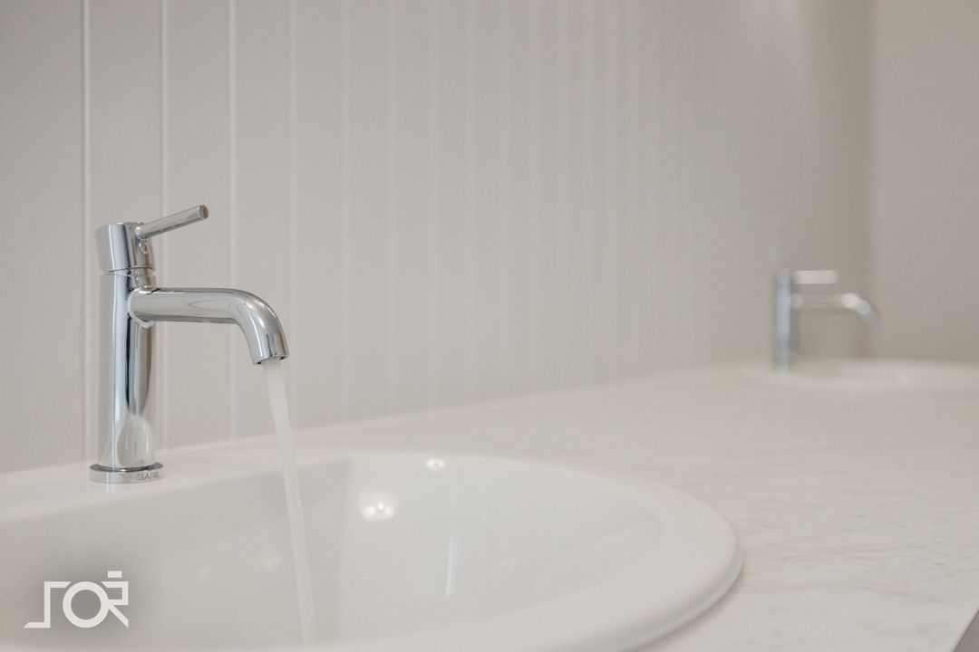 Une salle de bain avec deux lavabos et deux robinets.