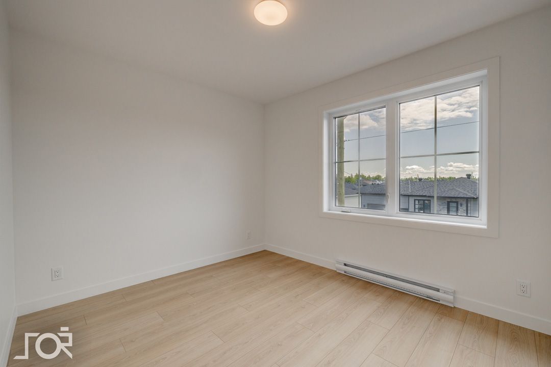 Une pièce vide avec une grande fenêtre et du parquet.