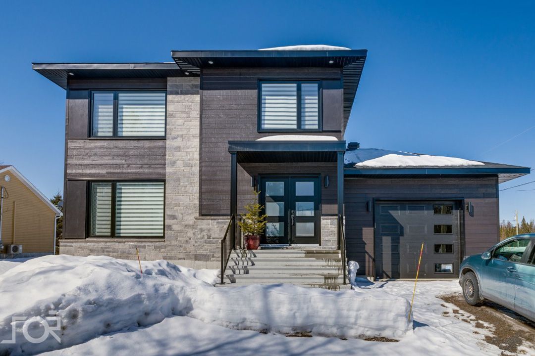 Une maison avec une voiture garée devant sous la neige.