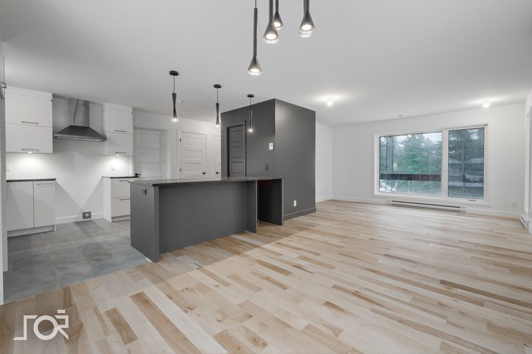 Une pièce vide avec du parquet et un grand îlot au milieu.