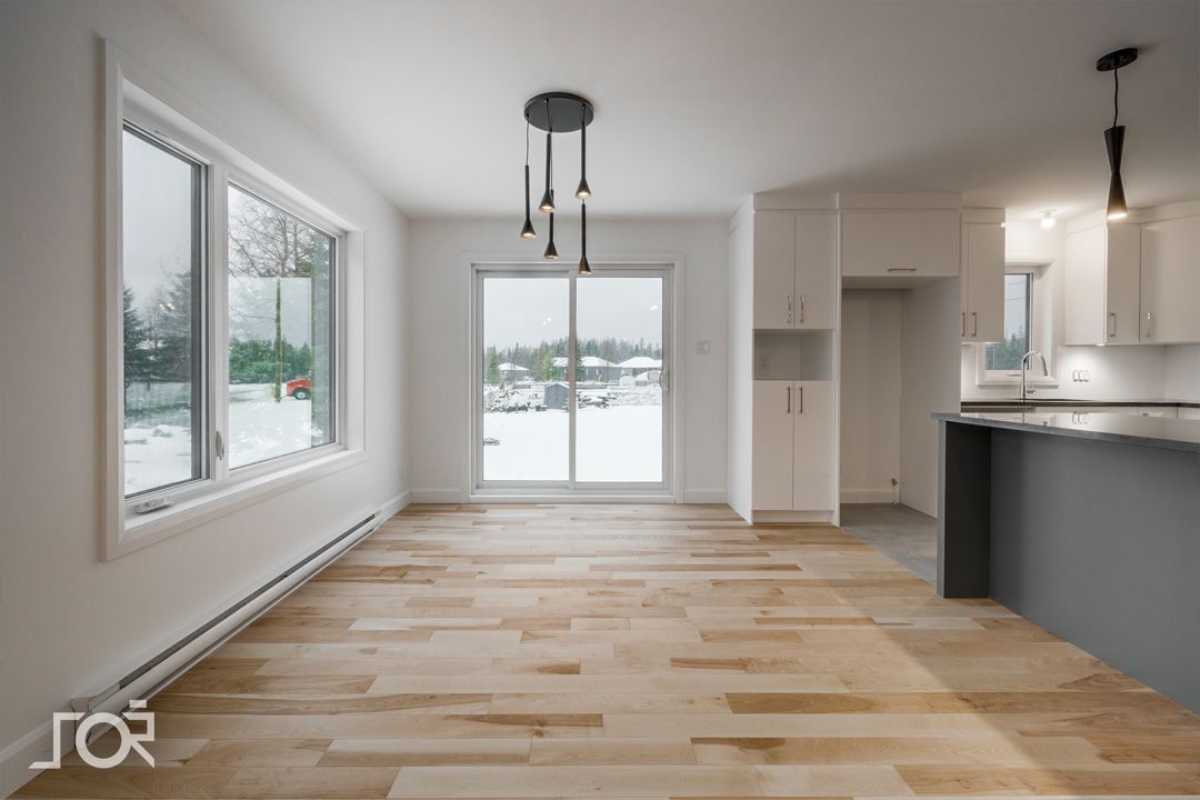 Un salon vide avec parquet et portes coulissantes en verre.