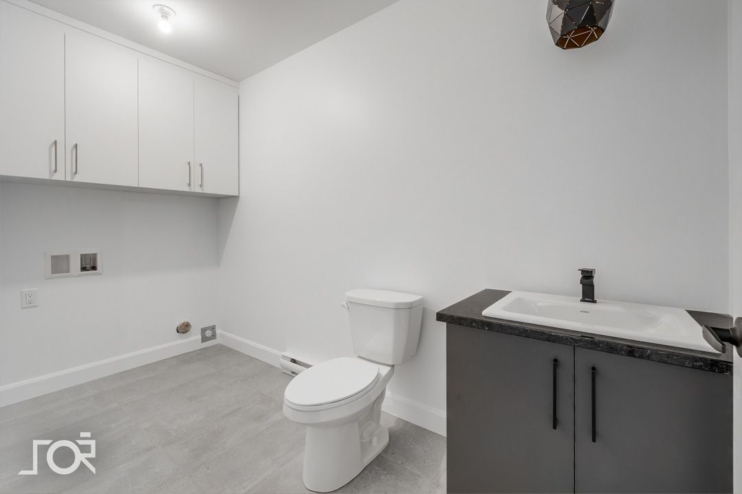 Une salle de bain avec WC, lavabo et meubles de rangement.