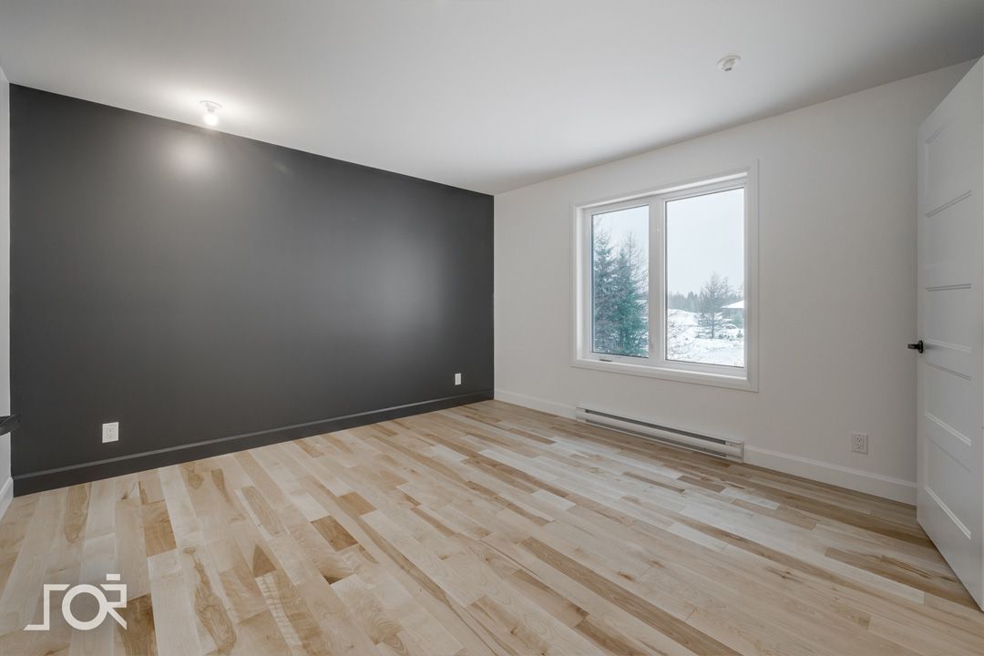 Une pièce vide avec du parquet et une fenêtre