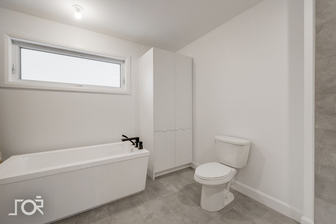 Une salle de bain avec baignoire, WC et fenêtre.