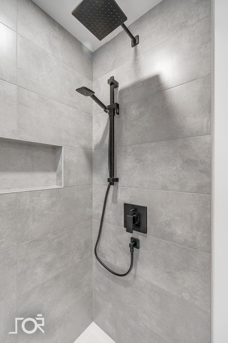 Une douche avec une pomme de douche noire et une pomme de douche noire.