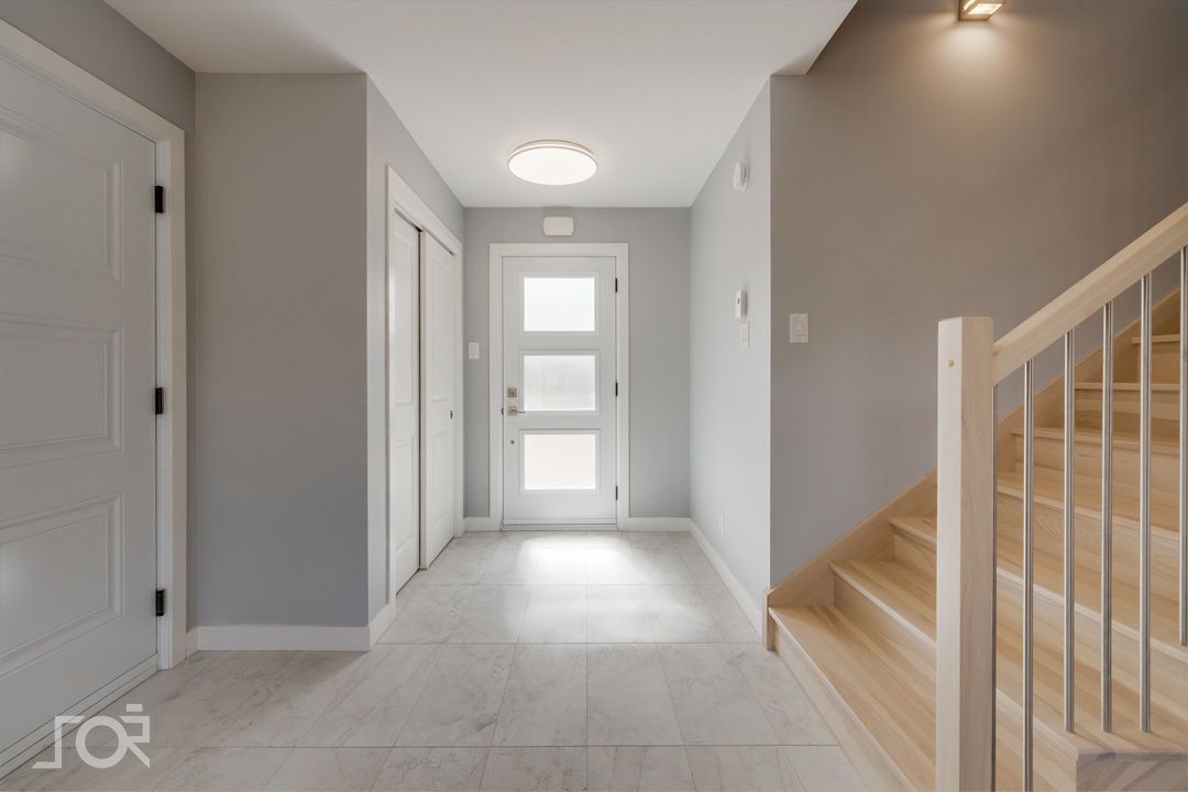 Un couloir avec une porte et des escaliers dans une maison