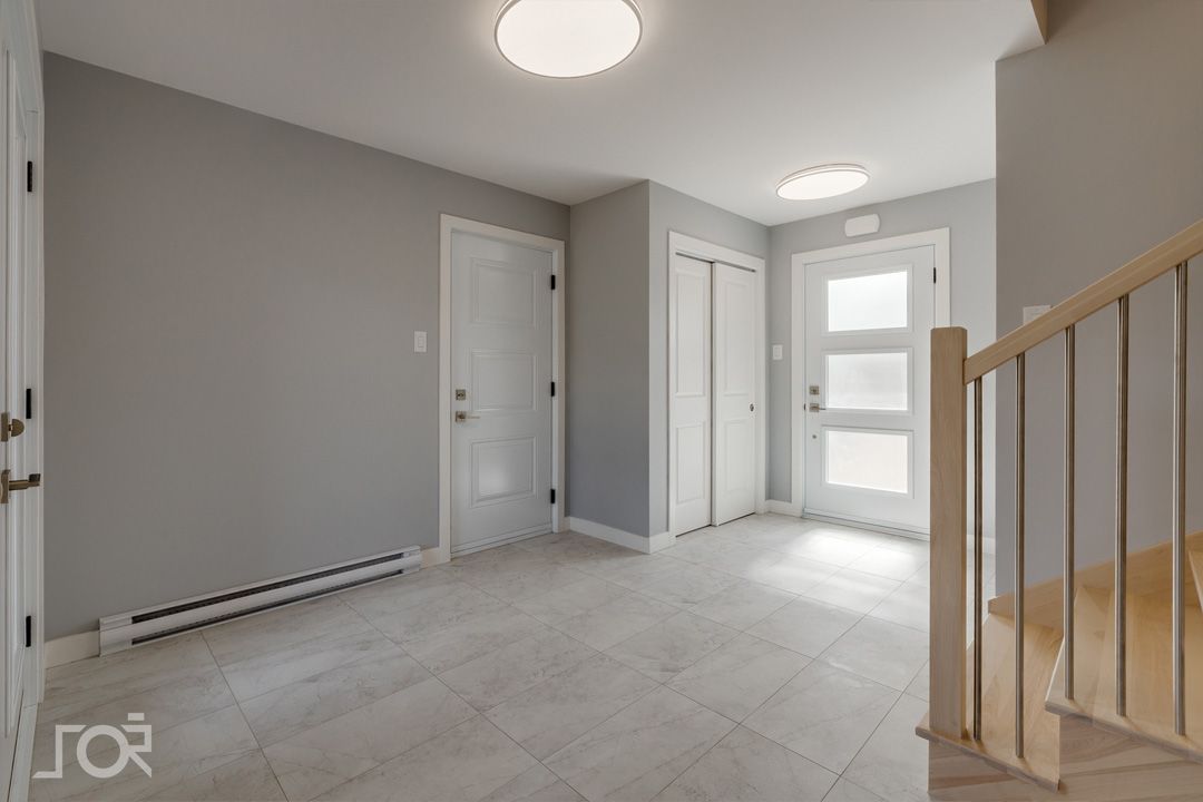 Un couloir vide avec des escaliers et une porte dans une maison.