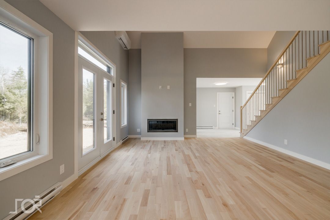 Un salon vide avec du parquet et une cheminée