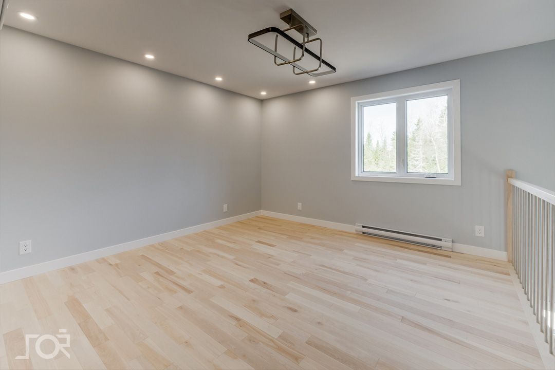 Une pièce vide avec du parquet et une fenêtre.