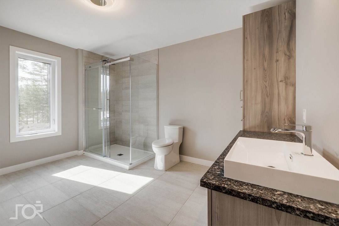 Une salle de bain avec lavabo, WC, douche et fenêtre.