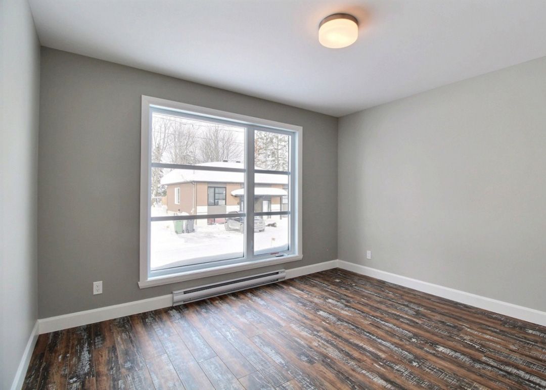 Une pièce vide avec du parquet et une grande fenêtre.
