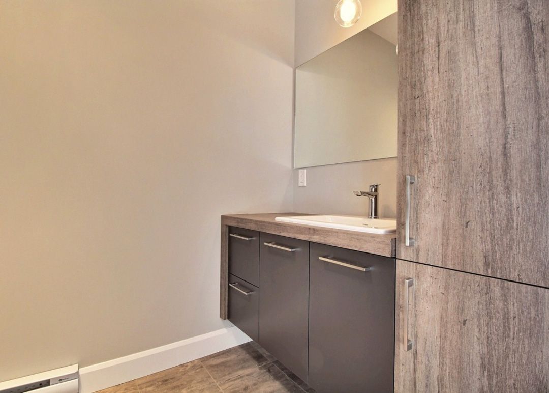 Une salle de bain avec lavabo, miroir et armoires.