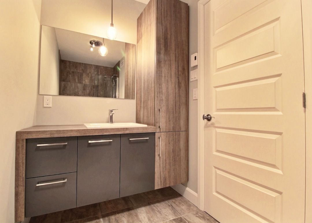 Une salle de bain avec lavabo, miroir et armoires.