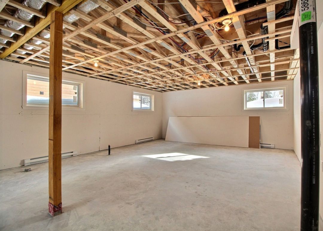 Un sous-sol vide avec un plafond en bois et quelques fenêtres.