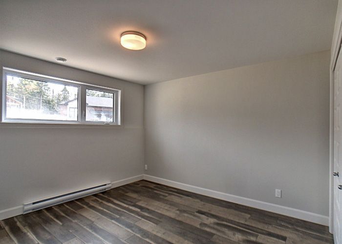 Une chambre vide avec un plancher en bois et une fenêtre.