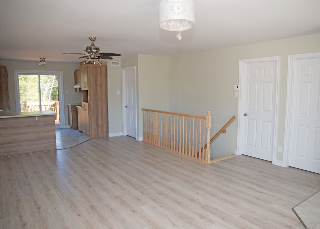Un salon vide avec un escalier en bois et un ventilateur de plafond.