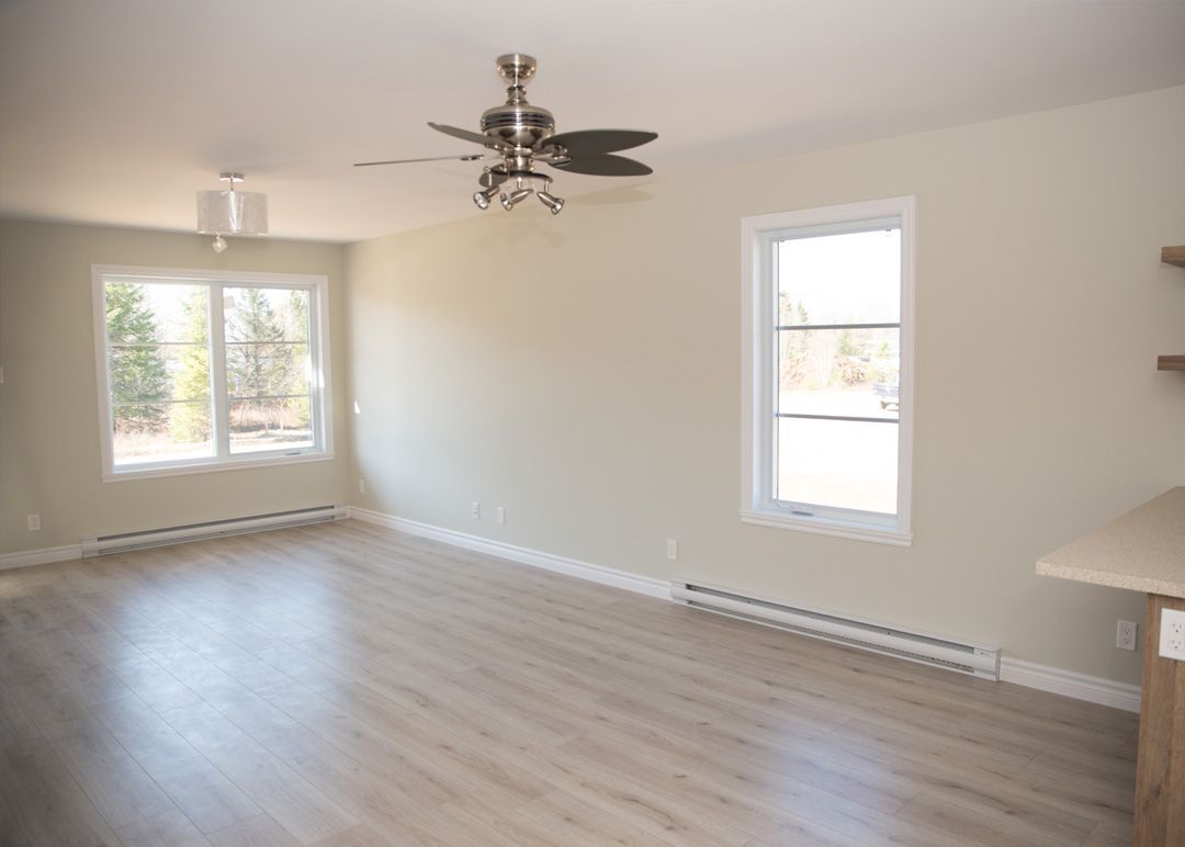 Un salon vide avec du parquet et un ventilateur de plafond.