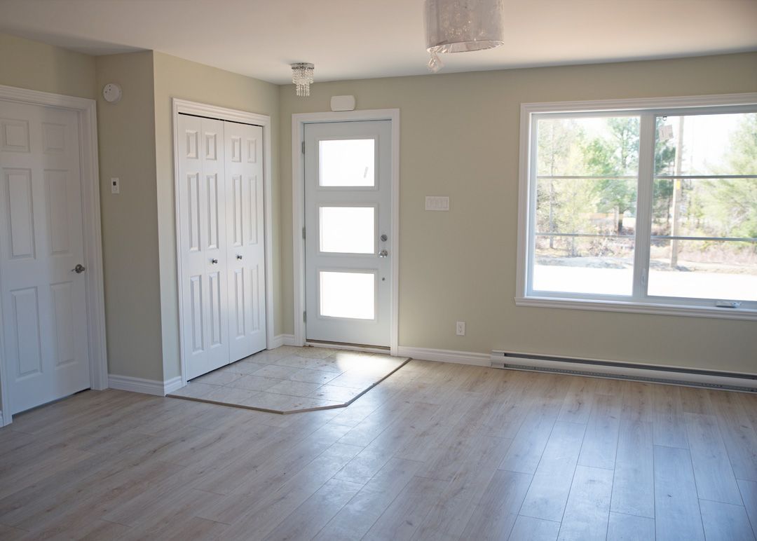 Un salon vide avec du parquet et une porte blanche