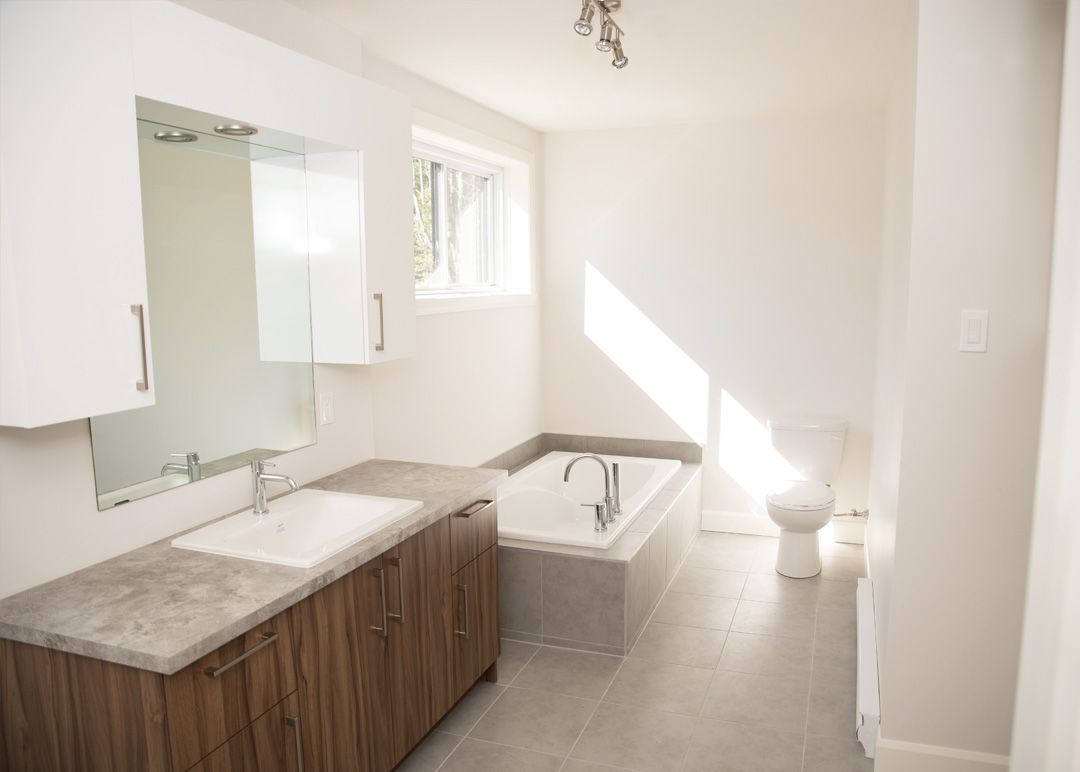 Une salle de bain avec baignoire, lavabo, toilettes et miroir.