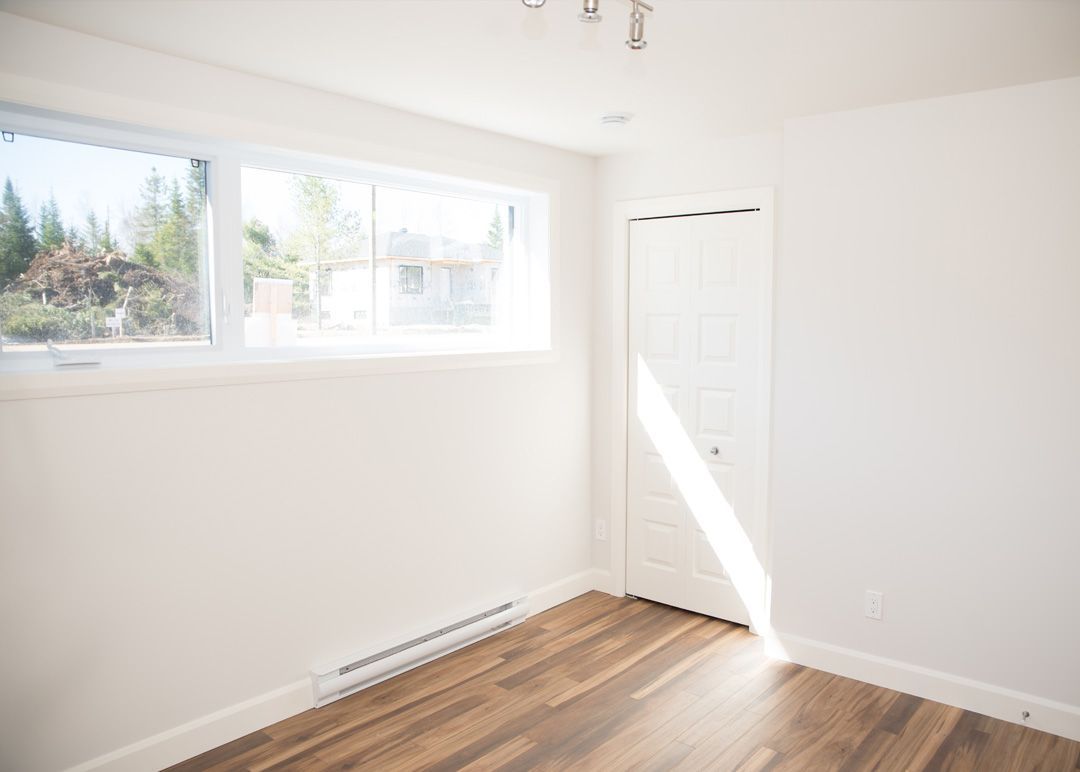 Une pièce vide avec du parquet et une fenêtre.