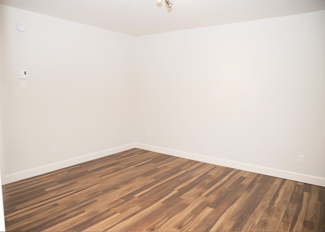Une pièce vide avec du parquet et des murs blancs.