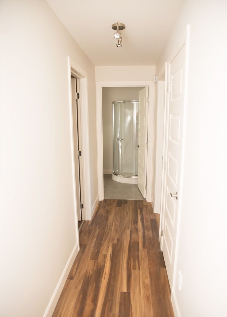 Un couloir avec parquet menant à une salle de bain.